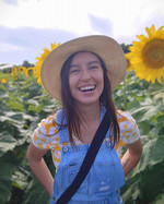Photo of Emily smiling in a sunflower field