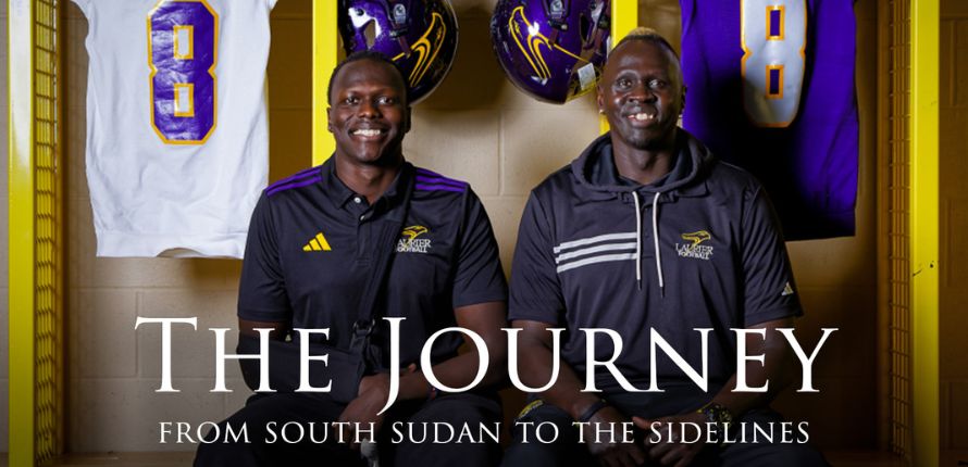 Two men sit in a lockeroom with football jerseys and helmets behind them. Text over the image reads The Journey: From South Sudan to the Sidelines.