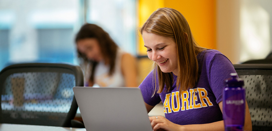 female student smiling at her laptop
