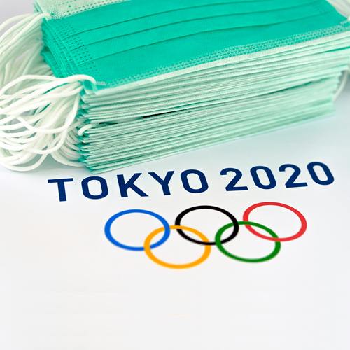 Olympics logo next to a stack of medical masks